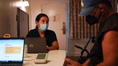 Physician assistant Samantha Kumpf talks with a transitional housing resident in Los Angeles during his doctor’s appointment in the same building as his apartment. October 2022.