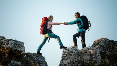 Backpackers helping each other across a gap