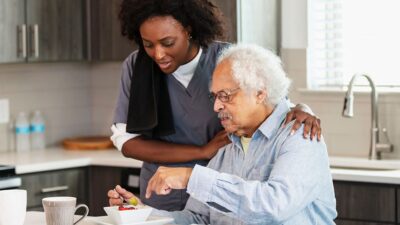 Elderly man with caregiver eating breakfast