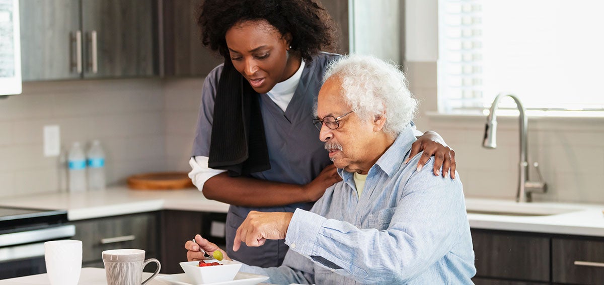 Elderly man with caregiver eating breakfast