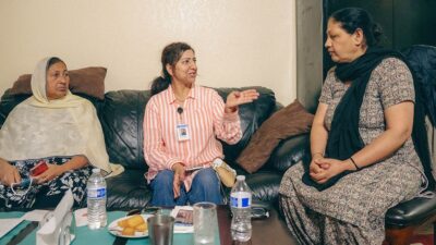 Community Health Worker Harjit Kaur, center, speaks with meat packing worker Manjit Kaur as her friend, Kulwant Kaur, looks on. Manjit Kaur is one of many Punjabi residents in Fresno who work at area meatpacking plants. Manjit Kaur expressed thanks for help she received getting an appointment with a Punjabi-speaking dentist after she became bedridden with tooth pain and had to miss work. Photo: Sahibjit Singh