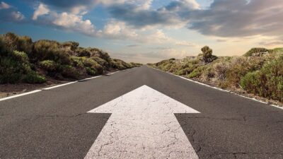 Road with an arrow painted in th emiddle, pointing to the horizon