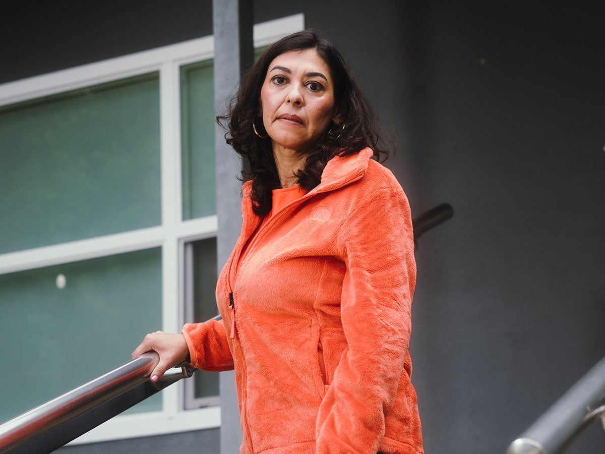 California Cap Health Costs - a woman stands on the stairs outside her home