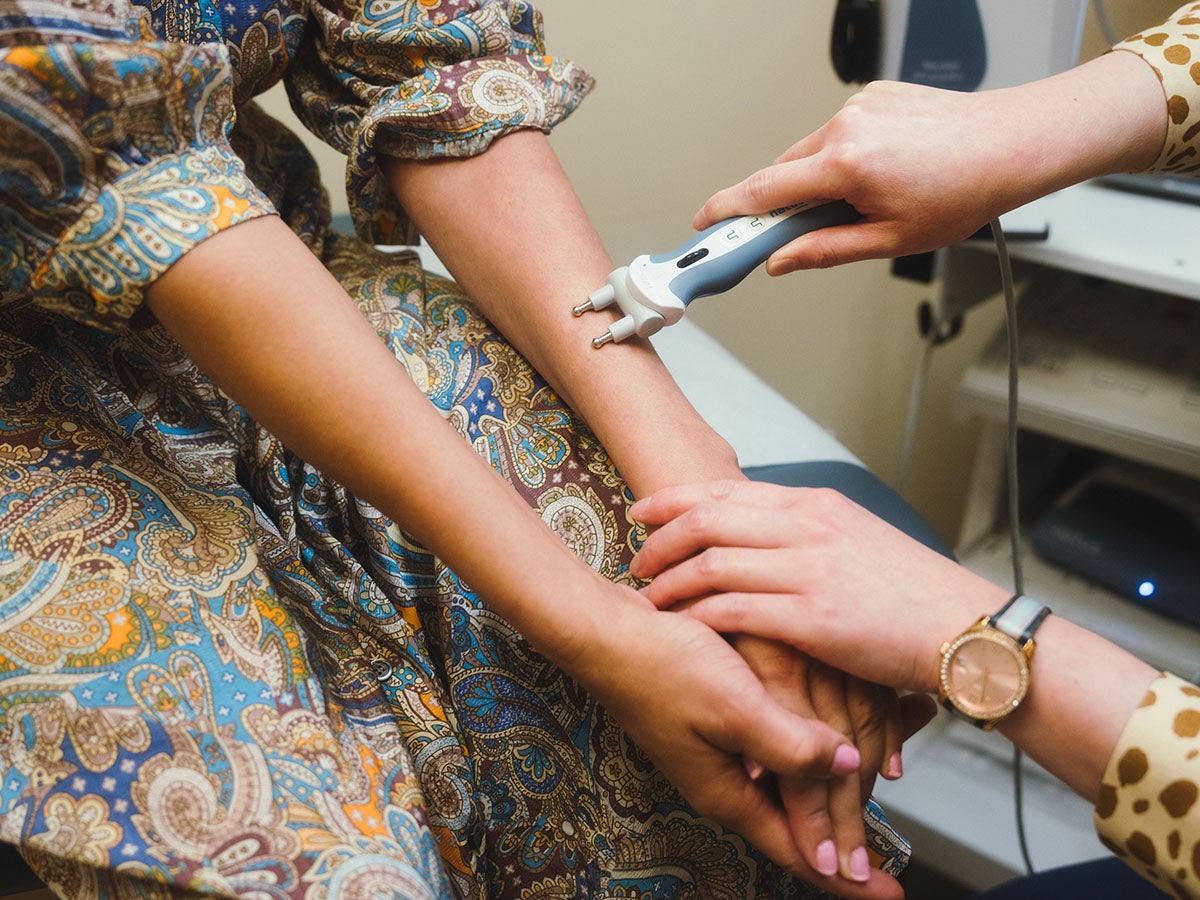 California cap on health costs: Doctor using EMG to check nerve muscle stimulation of patient.
