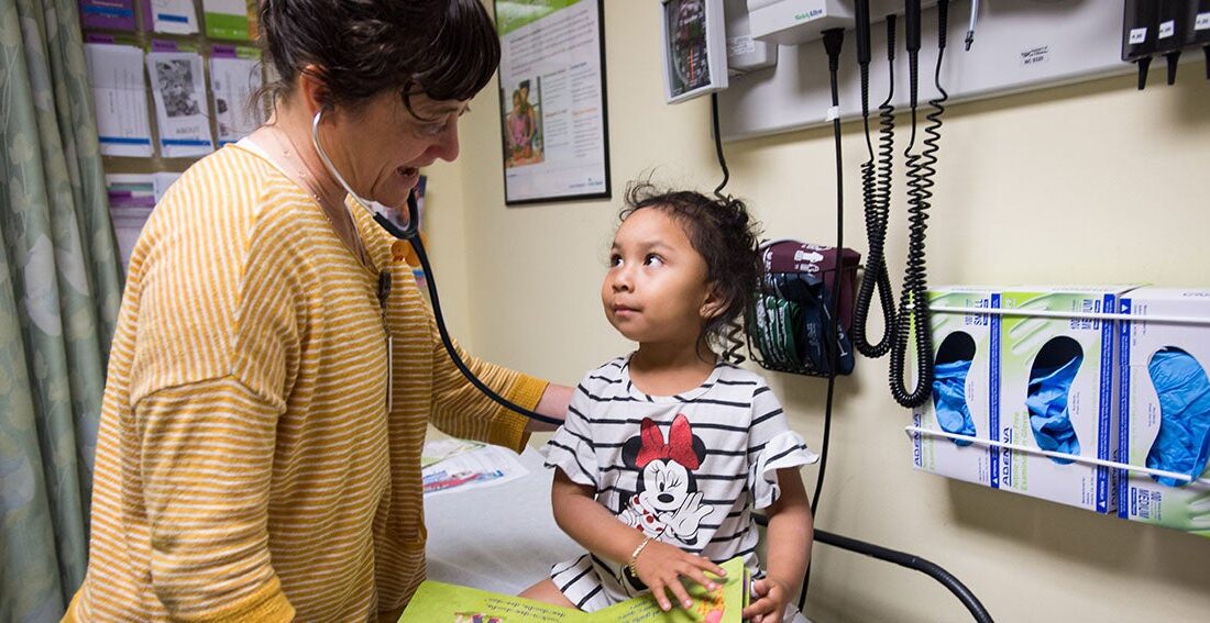 Doctor listens to heartbeat of small child