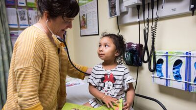 Doctor listens to heartbeat of small child