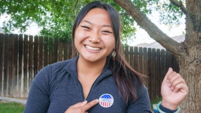 Youg woman happily displaying her "I Voted" sticker