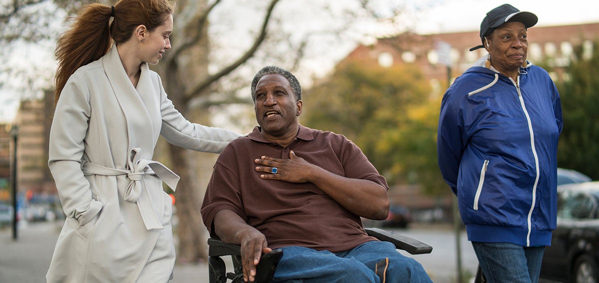 Young woman, older man in wheelchair, older woman walking