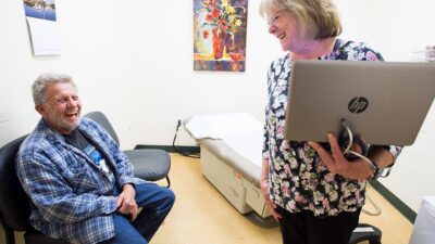 Patient and doctor laughing together diting a clinic visit