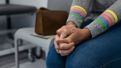 Woman's hands clenched together while waiting for medical care