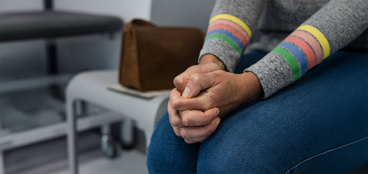 Woman's hands clenched together while waiting for medical care