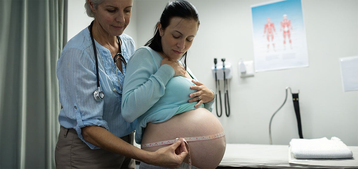 Midwife measures patient during an office visit.