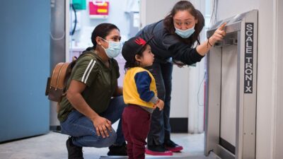 Medical practitioner shows child hoe a scale wotks while his mother watches.