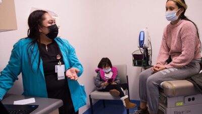Doctor talks to patiend while entering visit infomation into medical record.