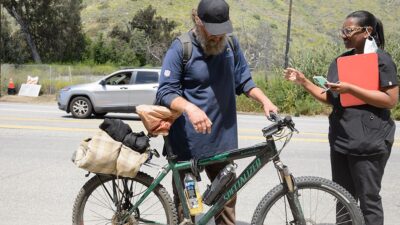 Street medicine practitioner talks to man experiencing homelessness.