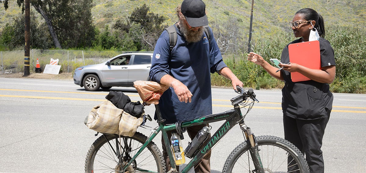 Street medicine practitioner talks to man experiencing homelessness.
