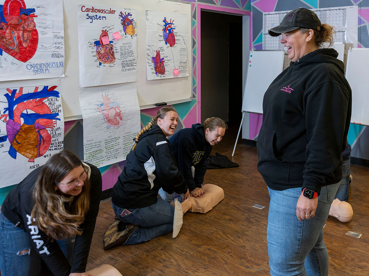 rural health worker shortage - A teacher instructs students on administering CPR.