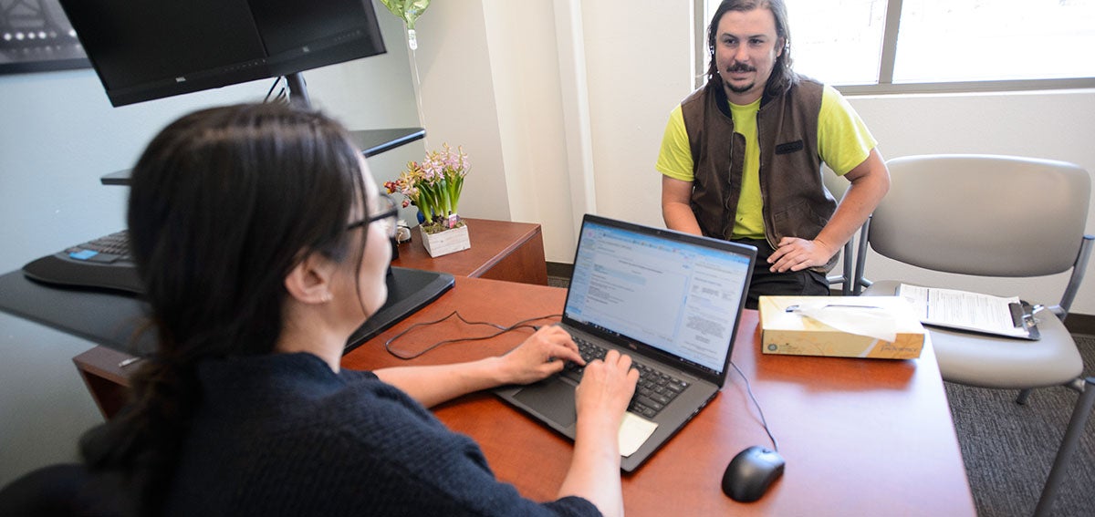 Provide talks to patient while taking notes on a laptop.