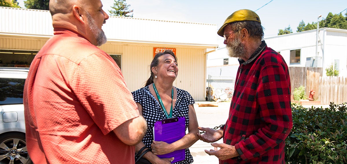 Community Health Workers talk to client outdoors