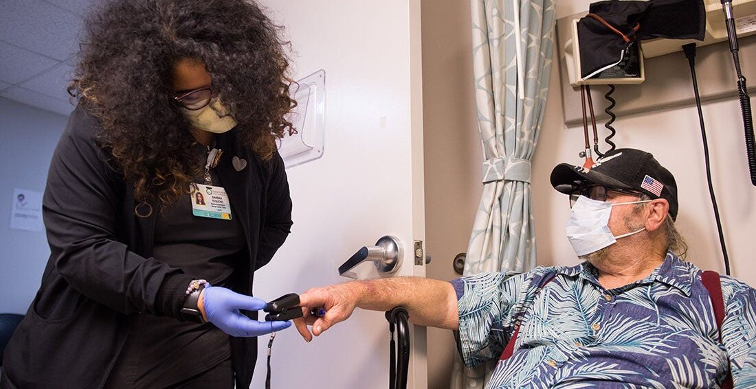 Medical assistant checks pulse on elderly patient in the clinic.