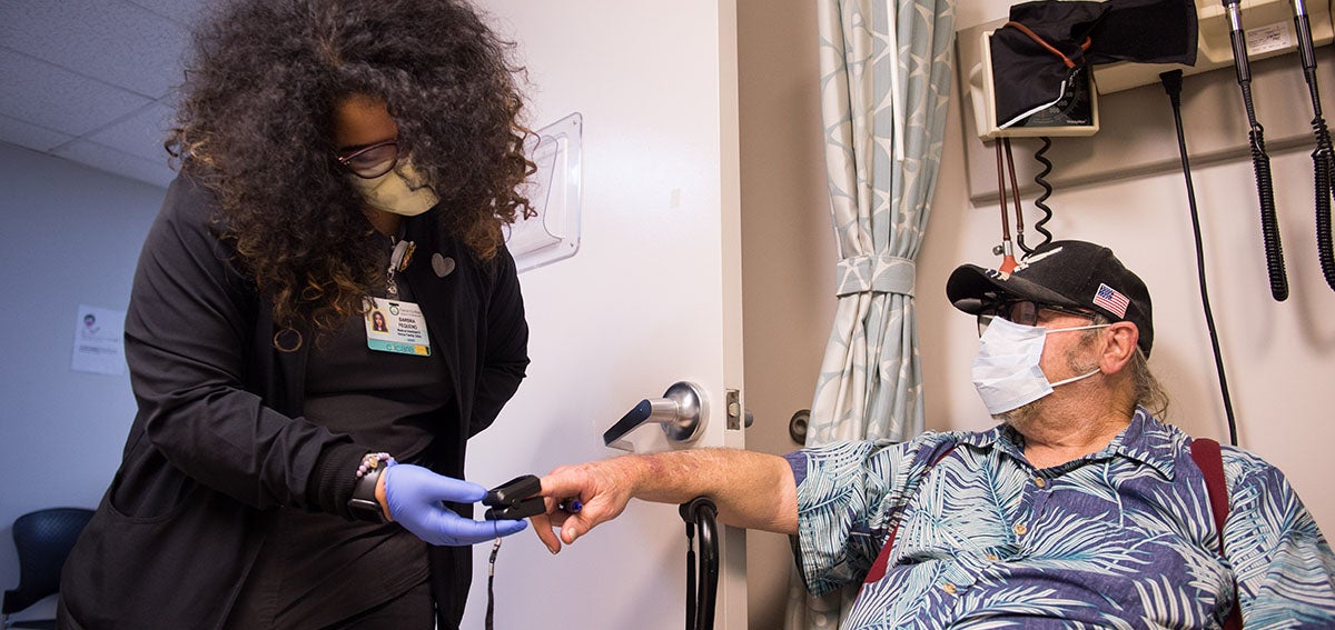Medical assistant checks pulse on elderly patient in the clinic.