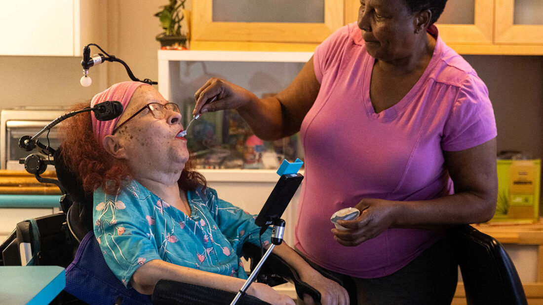 Caretaker Marie Locoh helps Cynde Soto at her home in Long Beach