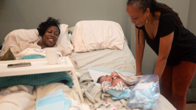 Mother and doula observe newborn at a birth center.
