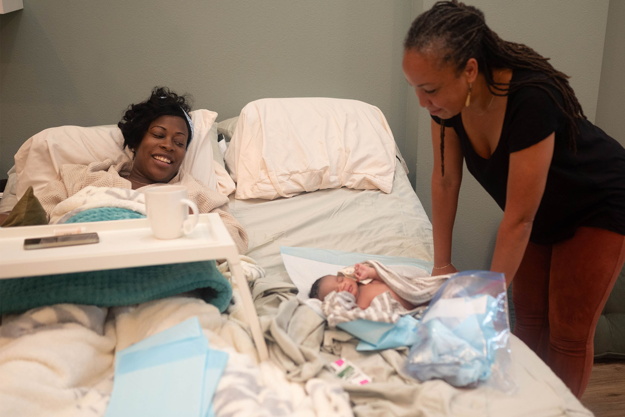 Mother and doula observe newborn at a birth center.