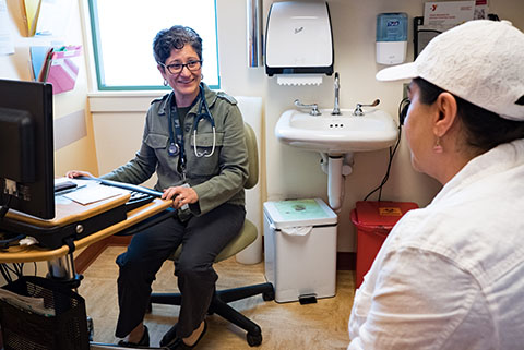 Doctor talks to Patient twhile endtering information into an Electronic Medical Record.,