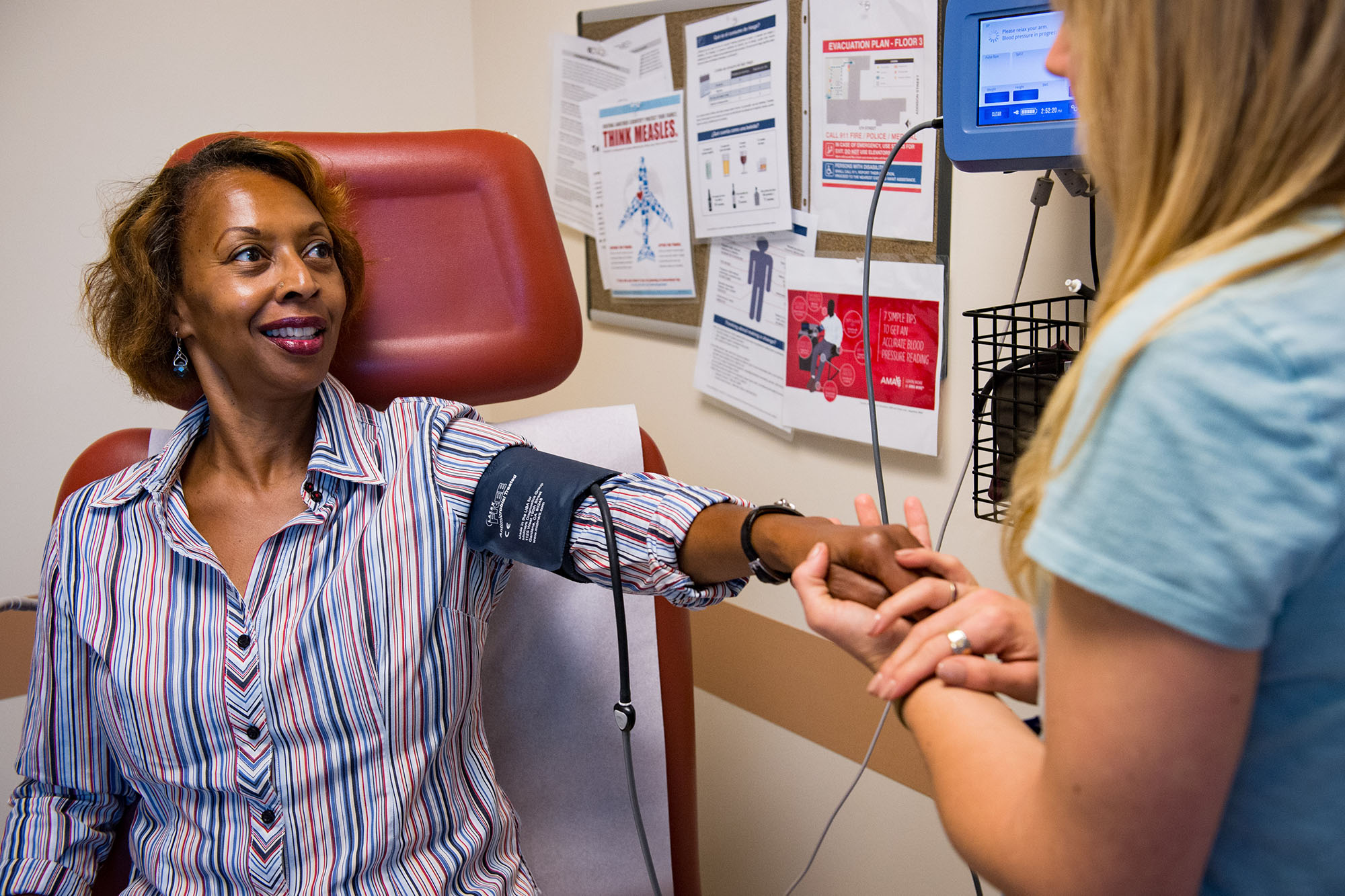 60 years of Medicaid - Middle aged woman having her blood pressure taken at a doctor's office.