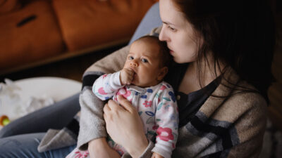 Mother looks pensive while holding baby.