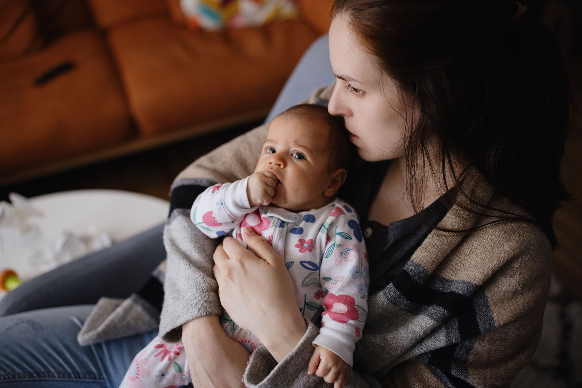 Mother looks pensive while holding baby.