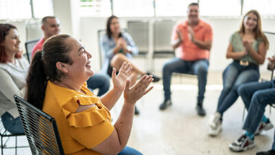 Group of people sitting in a circle smiling and claping