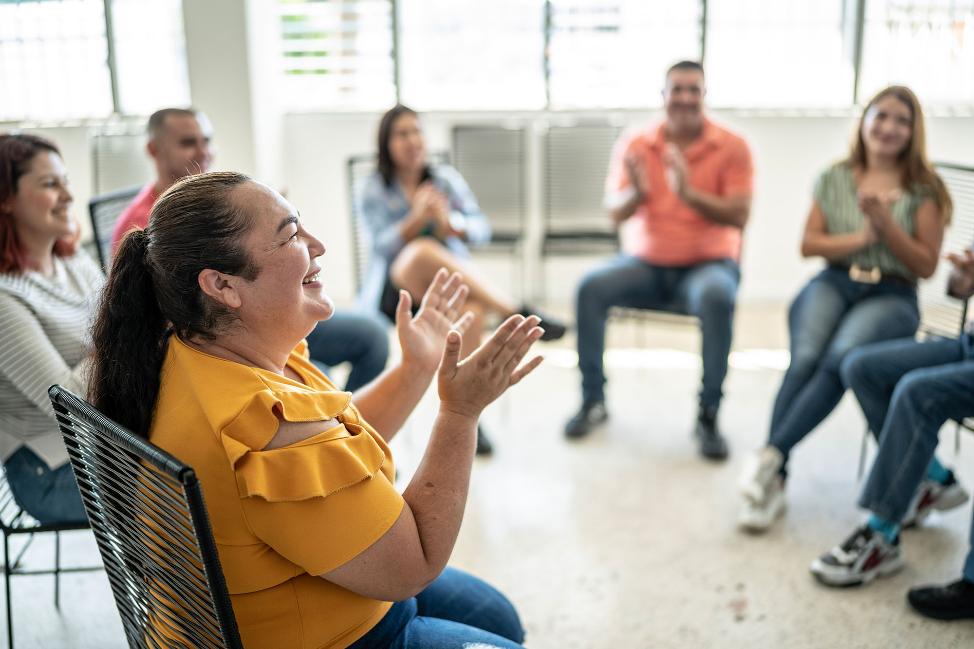 Group of people sitting in a circle smiling and claping