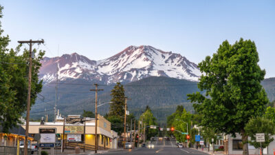 Mount Shasta, California, USA - June 17th 2025: Main street of Mount Shasta town leading towards Mount Shasta Volcano, at dusk in summer