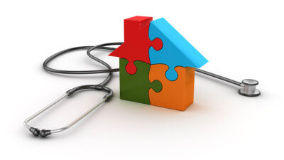 House made of four brighly colored puzzle pieces next to a stethoscope