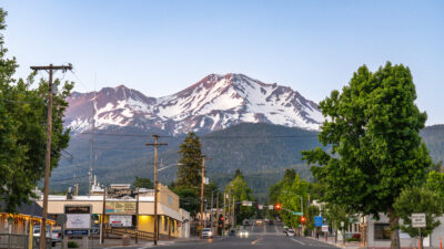 Mount Shasta, California, USA - June 17th 2025: Main street of Mount Shasta town leading towards Mount Shasta Volcano, at dusk in summer