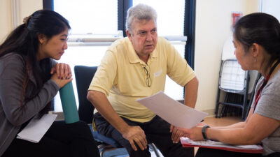Elderly male patient talks to clinicians.