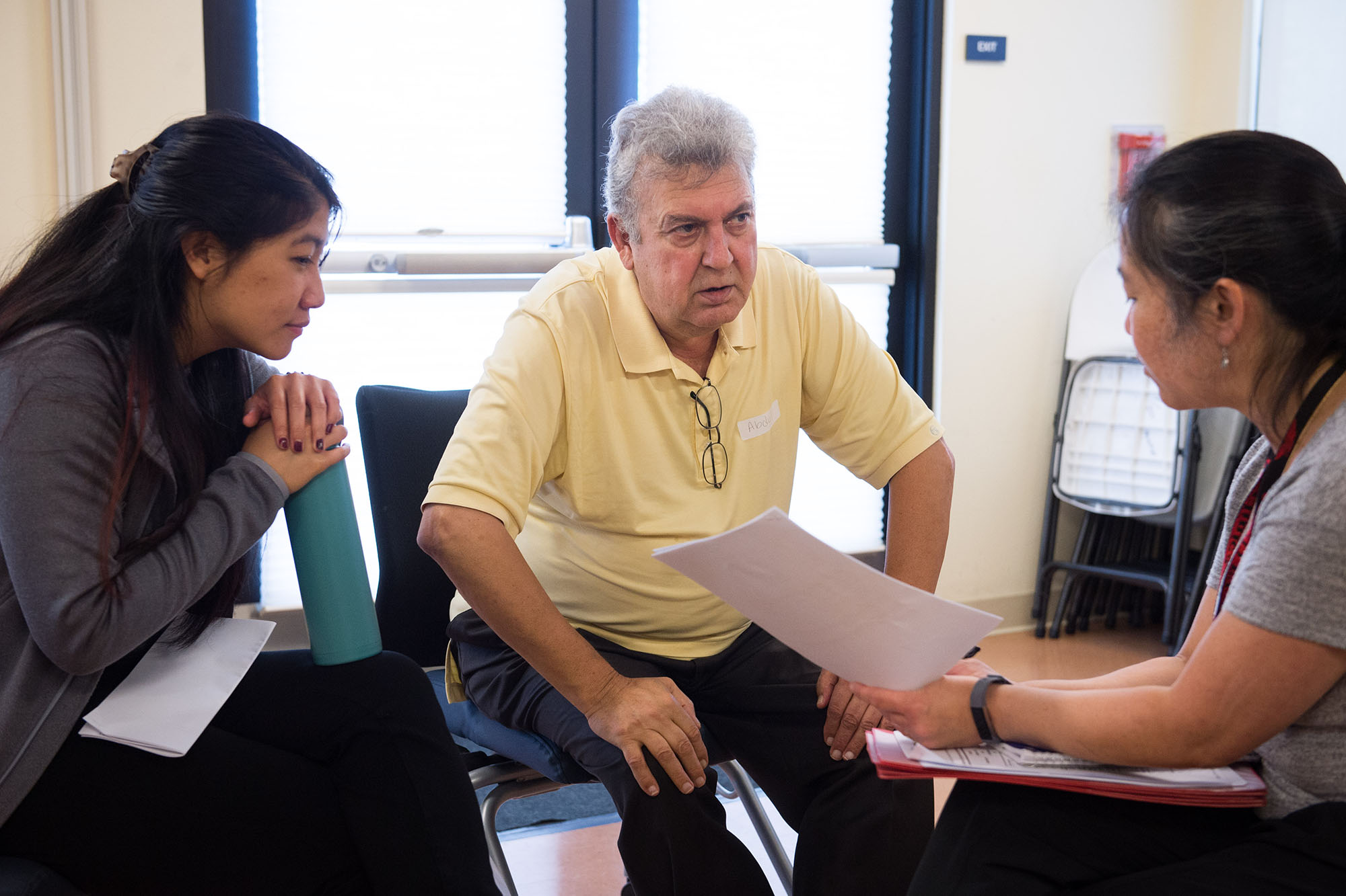 Elderly male patient talks to clinicians.