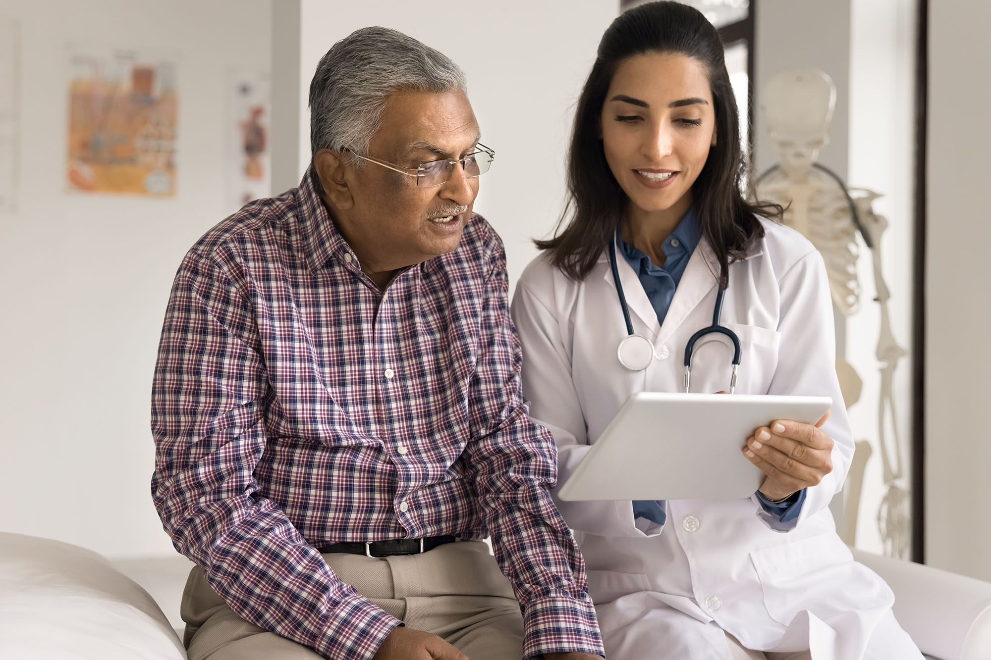 Elderly man looks at tablet with doctor