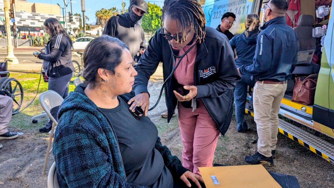 Los Angeles community clinic tax measure - a nurse practitioner examines an unhoused person outdoors