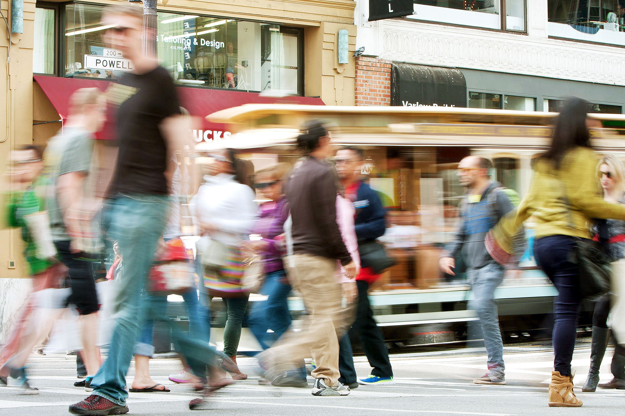 People walking tnear a cable car in San Francisco, CA.