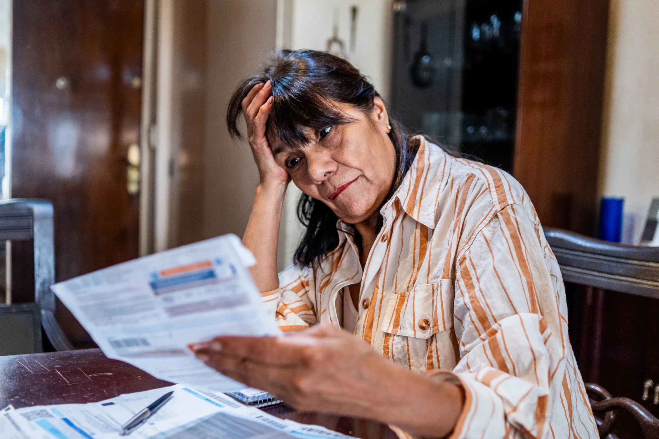 Distressed woman holds and looks at a hospital bill